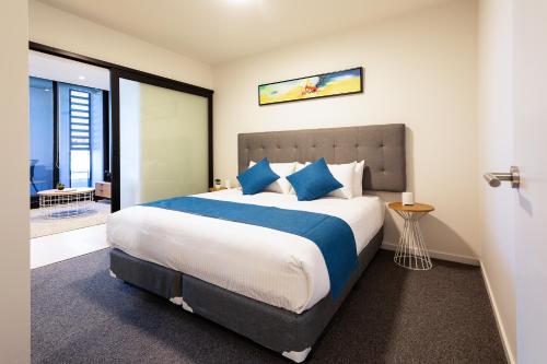 a bedroom with a large bed with blue pillows at Artel Apartments Brunswick in Melbourne
