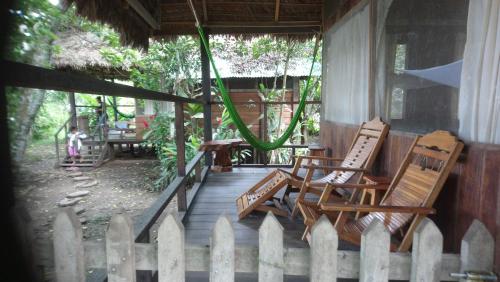 two chairs and a hammock on the porch of a house at Tambopata River in Puerto Maldonado