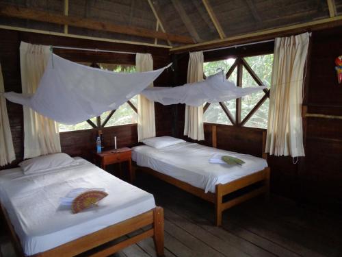 two beds in a room with nets hanging from the ceiling at Tambopata River in Puerto Maldonado