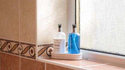 dos botellas de odorizantes sentadas en un estante en un baño en Pippin, Tranquil Scottish Cottage with Hot Tub en Airdrie