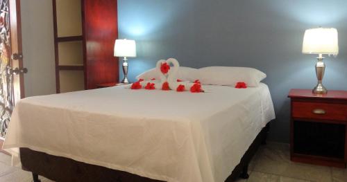 a bedroom with a white bed with red stuffed animals on it at Caribe Tesoro in West Bay
