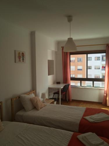 a bedroom with two beds and a desk and a window at Apartamento Familiar Lisboa Taguspark in São Marcos