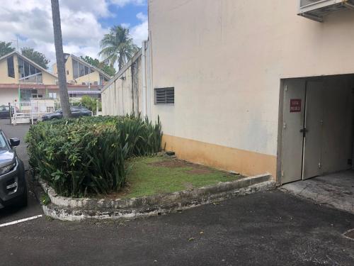 a parking lot with a building with a door and plants at EBT House, appartement, jacuzzi vue mer, 10 min aéroport et port in Baimbridge