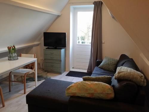 a living room with a couch and a table at Gastenverblijf appartement tussen Alkmaar en Hoorn in Oterleek