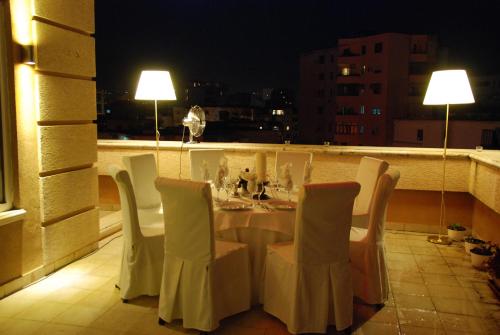 a dining room table with chairs and lamps at Hotel Doro City in Tirana
