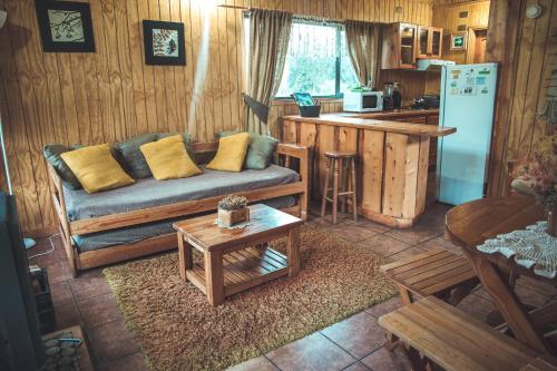 a living room with a couch and a kitchen at Cabañas Shangrila Aysen in Puerto Aisén