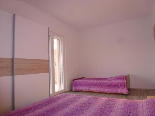 - une chambre avec un lit violet et une fenêtre dans l'établissement Apartmani Slavica, à Šibenik