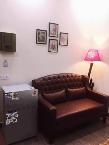 a brown couch sitting in a room with a lamp at Hayyat Luxury Hotel Apartments in Lahore