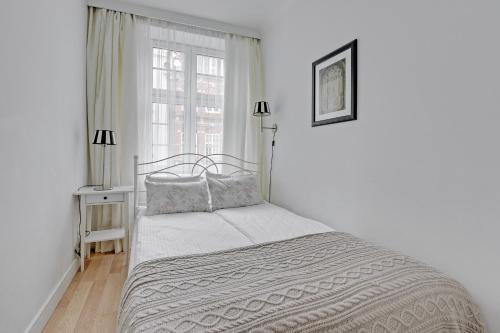 a white bedroom with a bed and a window at BE IN GDANSK Apartments - IN THE HEART OF THE OLD TOWN - Mariacka 31/33 in Gdańsk