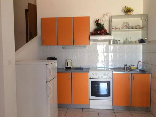 eine Küche mit Orangenschränken und einem weißen Herd in der Unterkunft Apartments Paladina in Mandre