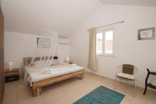 a bedroom with a bed and a chair and a window at Villa Putto in Vela Luka
