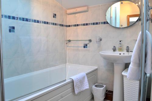 a bathroom with a bath tub and a sink at Petrock Holiday Cottages in Newton Saint Petrock