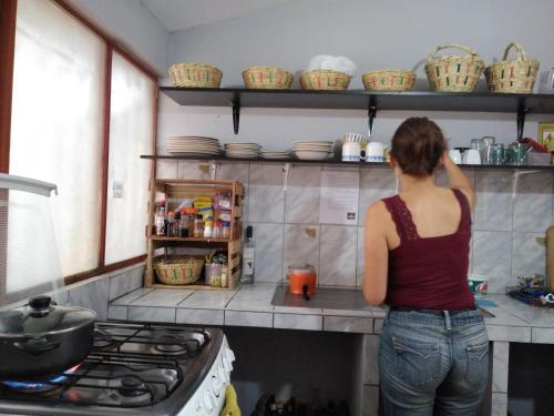 Uma mulher na cozinha a olhar para uma prateleira. em Estancia 311 Backpackers em Cajamarca