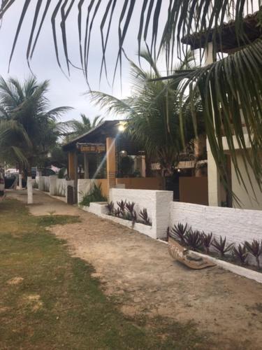 a building with a fence with palm trees in front of it at Chalé encontro das aguas in Barra do Cunhau