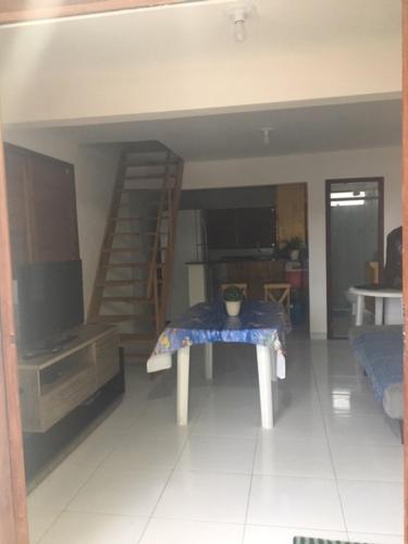 a living room with a table and a staircase at Chalé encontro das aguas in Barra do Cunhau