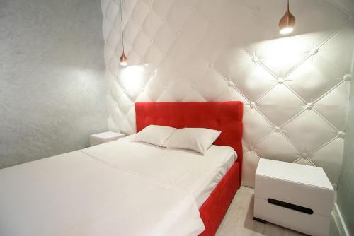 リヴィウにあるNOVA apartmentの赤いヘッドボードと白いベッドが備わるベッドルーム1室