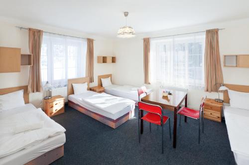 リベレツにあるPytloun Penzion Zelený Hájのベッド2台、テーブルと椅子が備わるホテルルームです。