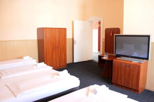 a room with three beds and a flat screen tv at Hotel-Pension Rheingold am Kurfürstendamm in Berlin