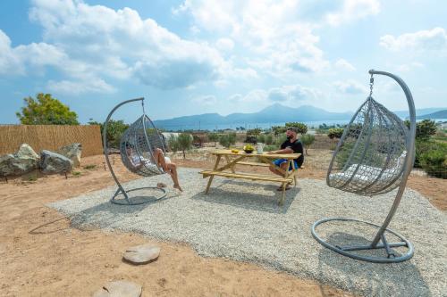 a man sitting at a picnic table with two metal sculptures at Aelia Suites in Adamas