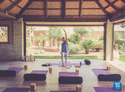 a man doing a yoga pose in a room with purple mats at Nexo Surf House in El Palmar