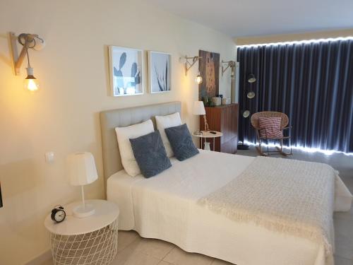 een slaapkamer met een groot wit bed met blauwe kussens bij Cabanas Apartments Sea View in Cabanas de Tavira