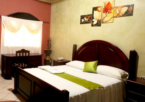 a bedroom with a bed with a green and white blanket at Apart Hotel K-Lisma in San Pedro Sula