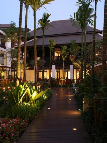 a walkway with palm trees in front of a building at Rarin Jinda Wellness Spa Resort in Chiang Mai