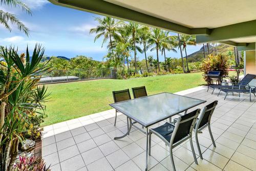 a patio with a table and chairs and a lawn at Hibiscus 006 - Hamilton Island in Hamilton Island