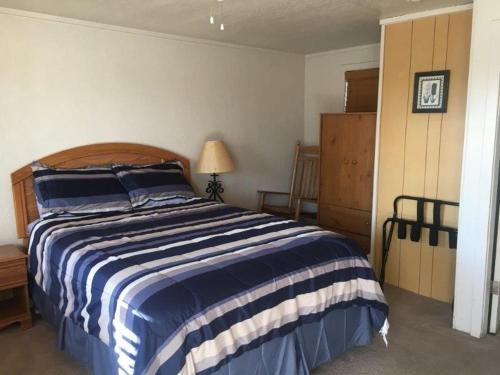 a bedroom with a bed with a blue and white striped blanket at Tyee Restaurant and Motel in Coupeville
