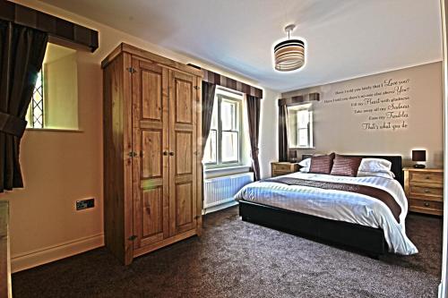 a bedroom with a bed and a large wooden cabinet at The Court House Inn in Thrapston