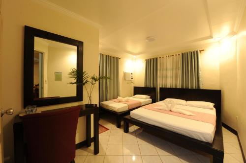 a hotel room with two beds and a mirror at Batanes Seaside Lodge & Restaurant in Basco