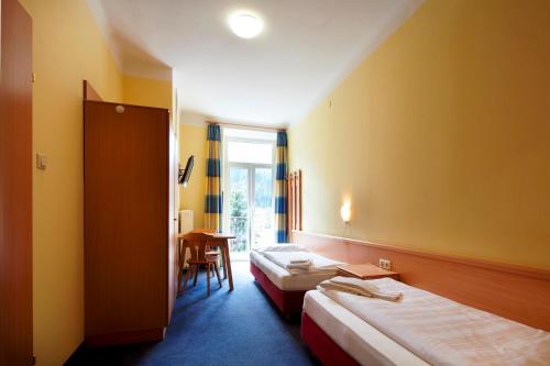 a hotel room with two beds and a table at Euro Youth Hotel & Krone in Bad Gastein