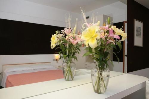 zwei Vasen voller Blumen auf einer Theke in einem Raum in der Unterkunft Hotel Isola di Lauria in Lauria Inferiore