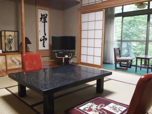 a living room with a black table and chairs at Oshi Ryokan in Nagano