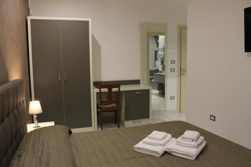una camera da letto con un letto e due asciugamani di Madigans rooms bed&breakfast a Lecce