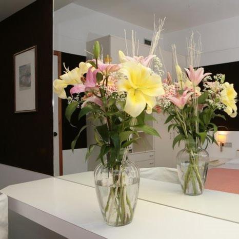 zwei Vasen voller Blumen auf dem Tisch in der Unterkunft Hotel Isola di Lauria in Lauria Inferiore