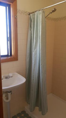 a bathroom with a shower curtain and a sink at Parndana Hotel Cabins in Parndana