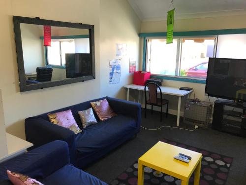 a living room with a blue couch and a mirror at Wander Inn Bunbury in Bunbury