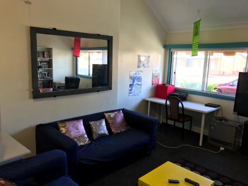 a living room with a blue couch and a mirror at Wander Inn Bunbury in Bunbury