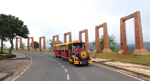 a small train driving down a road on a road at Aamby Valley City in Lonavala