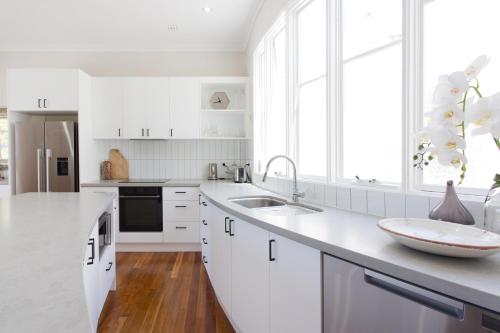 a white kitchen with white cabinets and a sink at Hidden Treasure in Fremantle