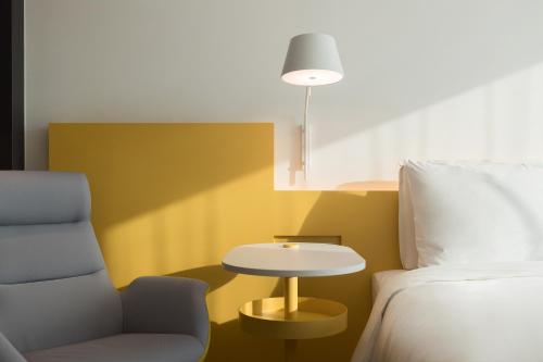 a room with a bed and a chair and a table at The Place Taipei in Taipei