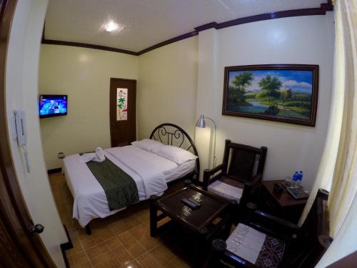 a small bedroom with a bed and a table and a desk at The Executive Villa Inn & Suites in Davao City