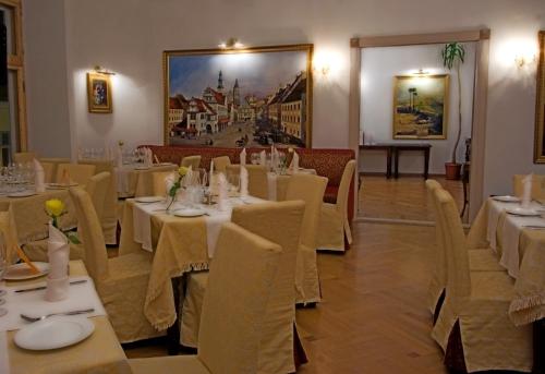 a restaurant with white tables and chairs and a painting at St.Olav Hotel in Tallinn