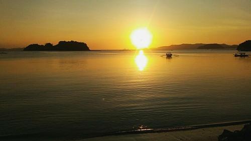 a sunset over a body of water with a boat at Acuario Beach Inn in San Vicente