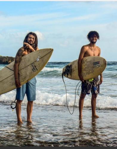 two men standing on the beach with surfboards at Becaville in Port Antonio