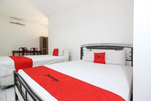 2 Betten in einem rot-weißen Zimmer in der Unterkunft RedDoorz near RS Sarjito Yogyakarta 2 in Yogyakarta