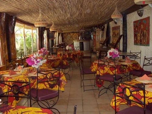 a room with tables and chairs with flowers on them at Hotel Club Safari in Mbour