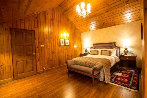a bedroom with a bed and a chandelier at The Elgin, Darjeeling - Heritage Resort & Spa in Darjeeling