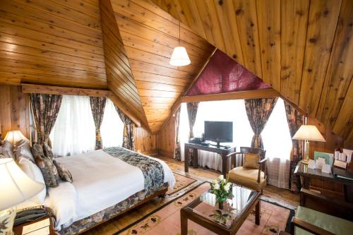 a bedroom with a bed and a wooden ceiling at The Elgin, Darjeeling - Heritage Resort & Spa in Darjeeling